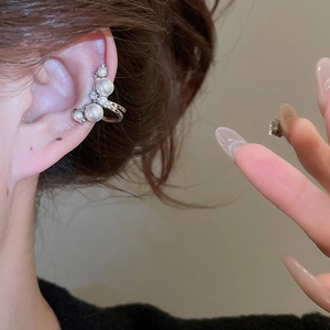 Close-up of a silver ear cuff with white pearls and sparkling zircons worn on ear