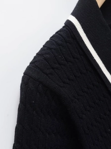 Close-up of black cable-knit texture with white contrast stripes on a polo collar