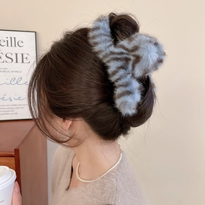 Close-up of blue and brown plush animal print hair claw clip worn on model's hair