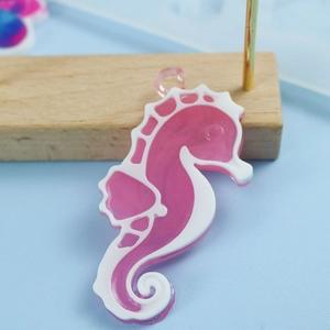 Vue macro d'un pendentif hippocampe en résine rose avec détails blancs et anneau