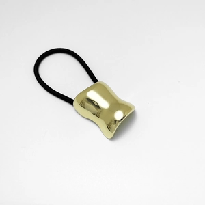 Détail de l'accessoire en métal doré poli en forme de U sur élastique noir
