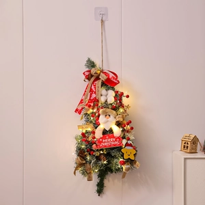 Detail of hanging Christmas teardrop wreath with LED lights, Santa doll and red bow