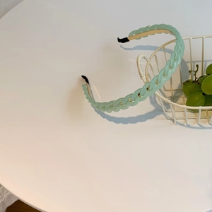 Detail of mint green chain hairband with black protective tips on a white table