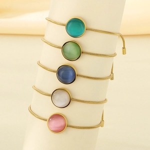 Détail de cinq bracelets serpent dorés avec des breloques en pierre naturelle multicolore