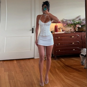 Detailed view of a white two-piece set featuring a halter bustier top and mini skirt
