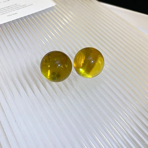 Close-up of translucent amber resin ball earrings with polished finish on a white background