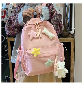Pink school backpack detail with plush star patches and cute white bear keychain accessory