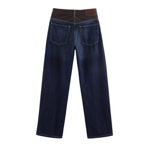 Détail d'un pantalon en denim bleu foncé avec taille patchwork en cuir marron et poches