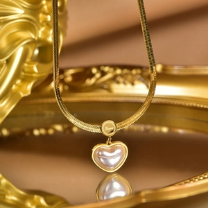 Macro detail of gold heart necklace with shell inlay and Love engraved pendant tag