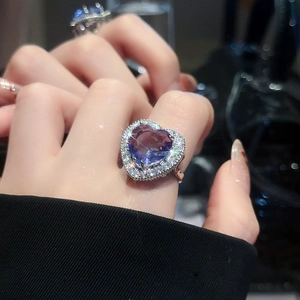 Close-up of a silver heart ring with a blue-purple gemstone and halo of zircons
