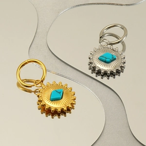 Fashionable gold and silver sunburst hoop earrings featuring a diamond turquoise center