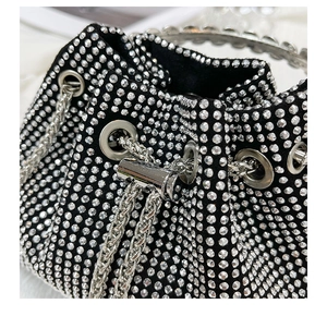 Close-up of sparkling black rhinestone bucket bag with metal drawstring and handle detail