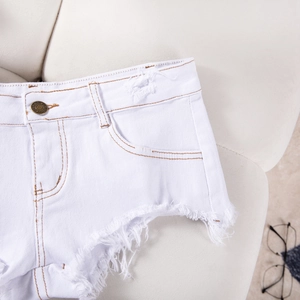 Dettaglio macro di pantaloncini bianchi in denim con bottone in rame e cuciture a contrasto