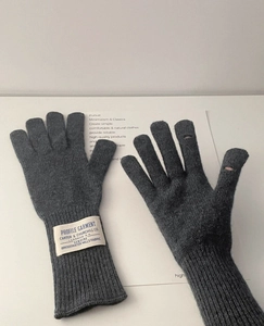 Detalle de guantes de lana gris oscuro que muestra el tejido de canalé y la ranura táctil