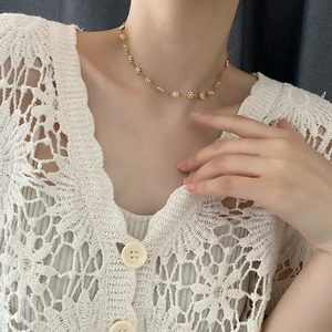 Golden necklace with white daisy floral pendants worn on neck for a fresh summer look