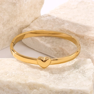 Polished 18K gold-plated heart-shaped stainless steel bangle on minimalist stone base