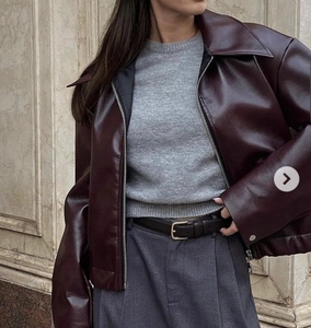 Detailed shot of a dark burgundy faux leather jacket with silver zippers and wide lapels