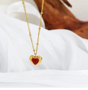 Macro detail of a 3D red heart pendant with triple-layered gold wavy borders