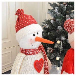 Close-up of plush Christmas snowman doll with heart detail and festive knit scarf
