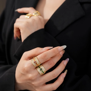 Close-up of gold-plated wide band ring featuring emerald-cut stones and white zircon