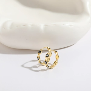 Detail of 14K gold plated evil eye hoop earrings with enamel inlay on white ceramic