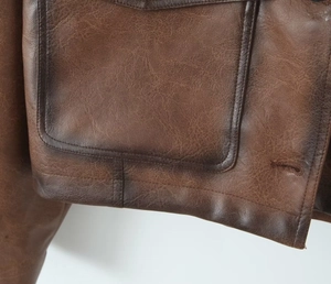 Detail van vintage bruin leren jas met textuur en stiksels van de zak van dichtbij
