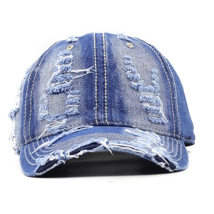 Detail of distressed blue denim baseball cap with vintage frayed holes and yellow stitching