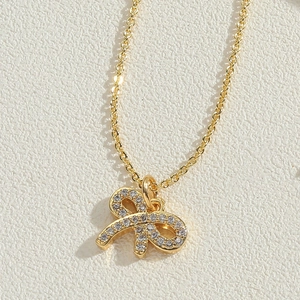 Macro detail of a gold bow pendant necklace featuring sparkling cubic zirconia stones