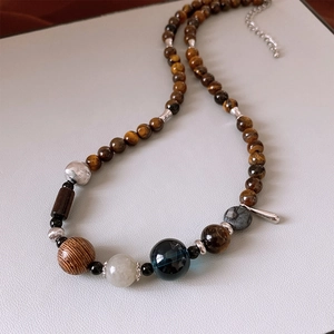 Detailed close-up of tiger eye stone and wooden beads on a vintage style pendant necklace
