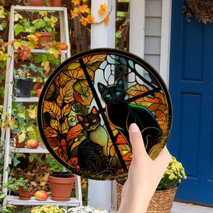 Close-up of circular acrylic suncatcher featuring black cats and autumn leaves decoration