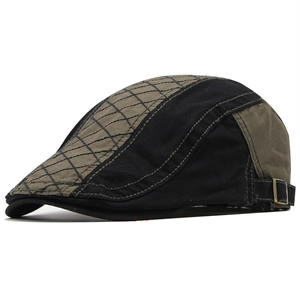 Detail view of cotton beret featuring patchwork design and adjustable bronze metal buckle