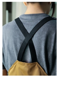 Detail view of the crisscross black fabric straps on a brown canvas work apron back