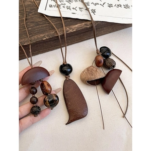 Détail d'un collier en bois vintage avec pendentif géométrique brun irrégulier et perles