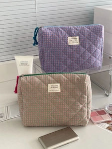 Detail of quilted checkered toiletry bags with soft fabric texture and zipper pulls