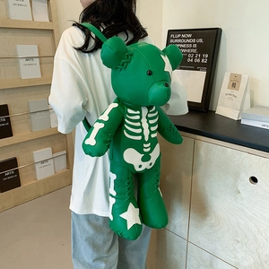 Fashionable green bear backpack with white skeleton pattern worn by a model in a studio