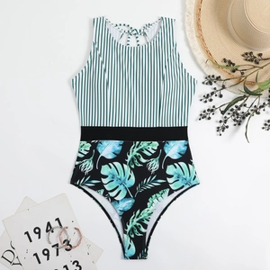 Detailed flat lay of striped one-piece swimsuit with tropical leaf print and black waistband
