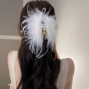 Close-up of fluffy white ostrich feather hair claw clip on brunette wavy hair