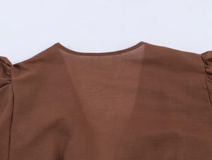 Gros plan d'un col en V élégant avec insert en mesh sur une robe marron ethnique