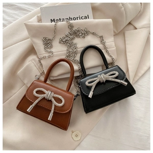 Detail of candy-colored patent leather bags with rhinestone bows and metal chain straps