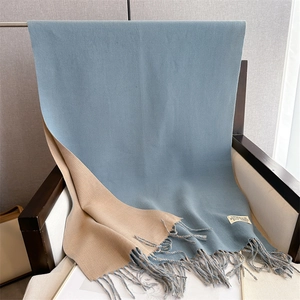 Detailed shot of two-tone beige and blue cashmere-like scarf draped on wooden chair