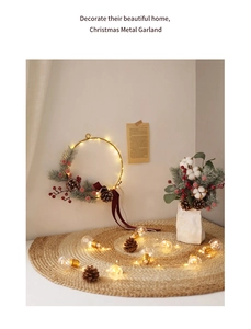 Detailed view of glowing Christmas wreath with gold metal hoop, pine cones and LED lights