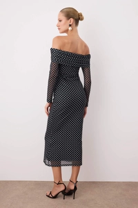 Detail of sheer mesh off-shoulder dress with white polka dots and elegant ruffled neckline