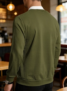 Rear view of an olive green waffle texture long-sleeve polo shirt in a cozy cafe setting