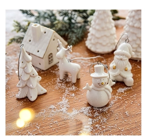 Detailed view of white ceramic Christmas tree ornaments with gold accents on wood