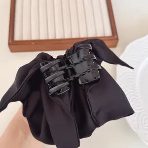 Detail of elegant black satin ribbon bow hair claw clip on a decorative tray