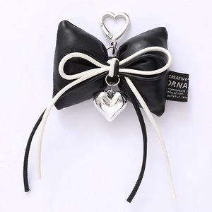 Close-up of black PU leather bow keychain with heart charm and creative fabric label