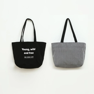 Close-up of canvas tote bag featuring Young wild and free print and striped patterns