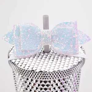 Close-up of a white glitter bow straw topper accessory for tumblers on white background