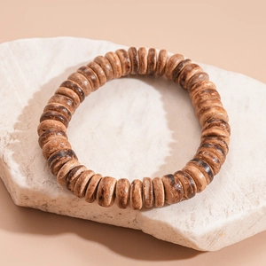 Detailed close-up of natural wood beads on stone, showing unique grain and organic texture