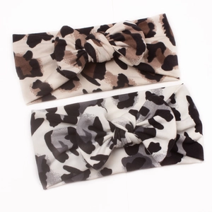 Detail of two leopard print baby headbands with bows in brown and grey soft fabric